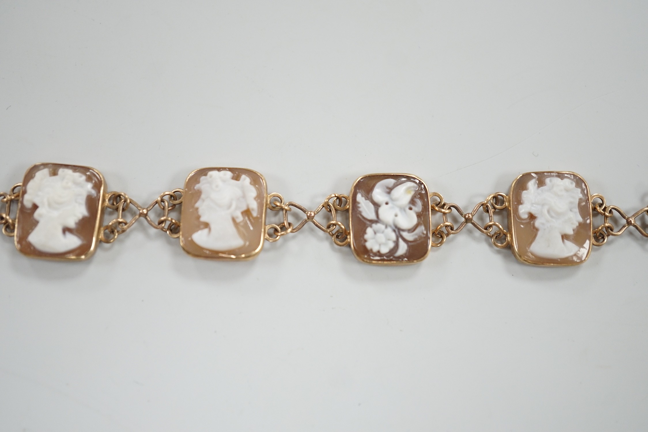 A 1970's 9ct gold and seven cameo panel set bracelet, carved with busts of ladies or flowers, 18cm, gross weight 10.3 grams.